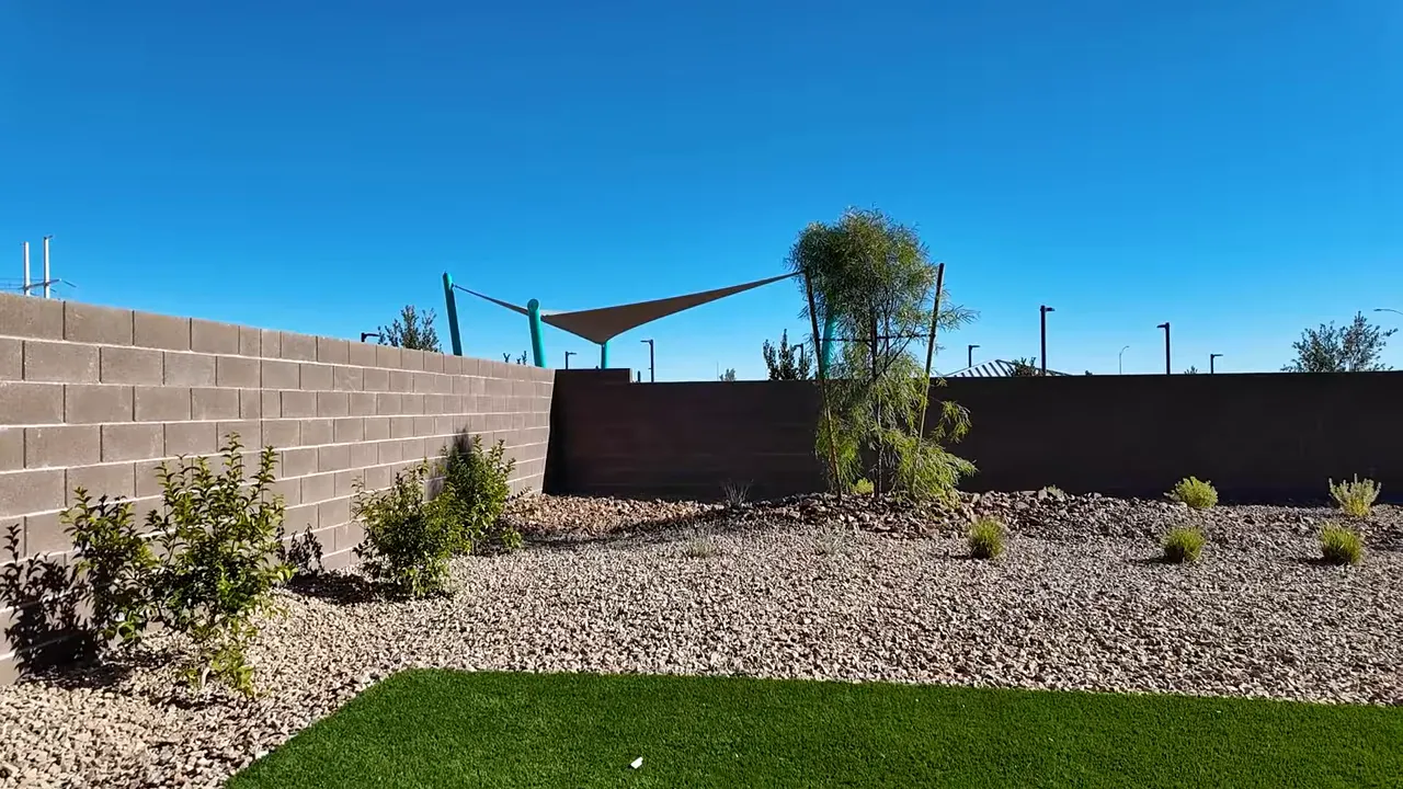backyard with artificial turf, rock landscaping and a block wall showing pool potential