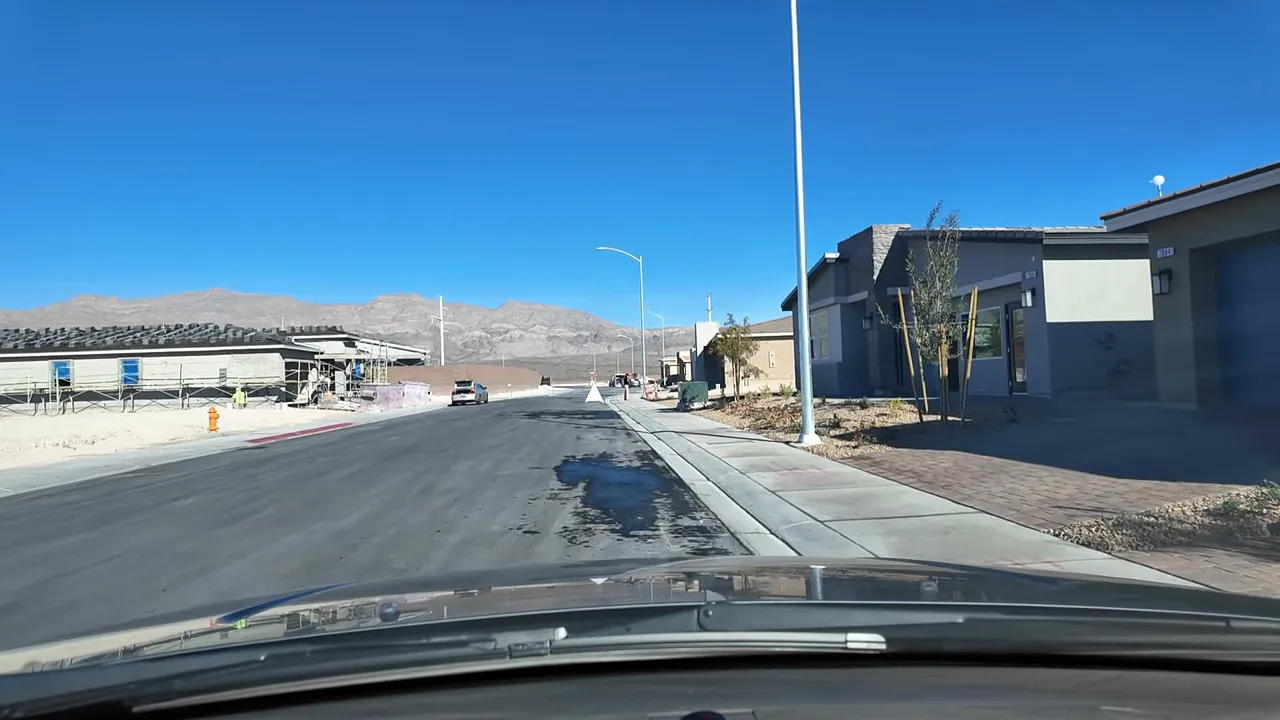Street-level view of model homes, sidewalk and mountain backdrop in a new Heartland Grove neighborhood