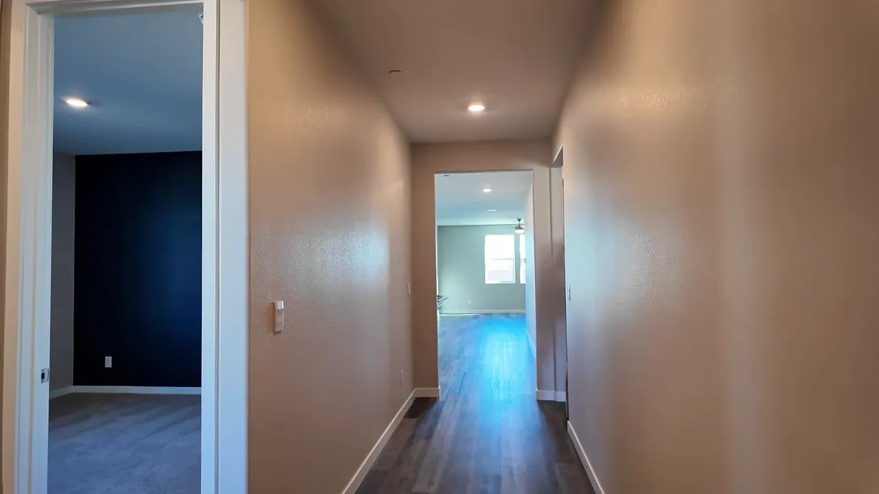 Hallway looking into open living area with wood-look flooring in a DR Horton model home