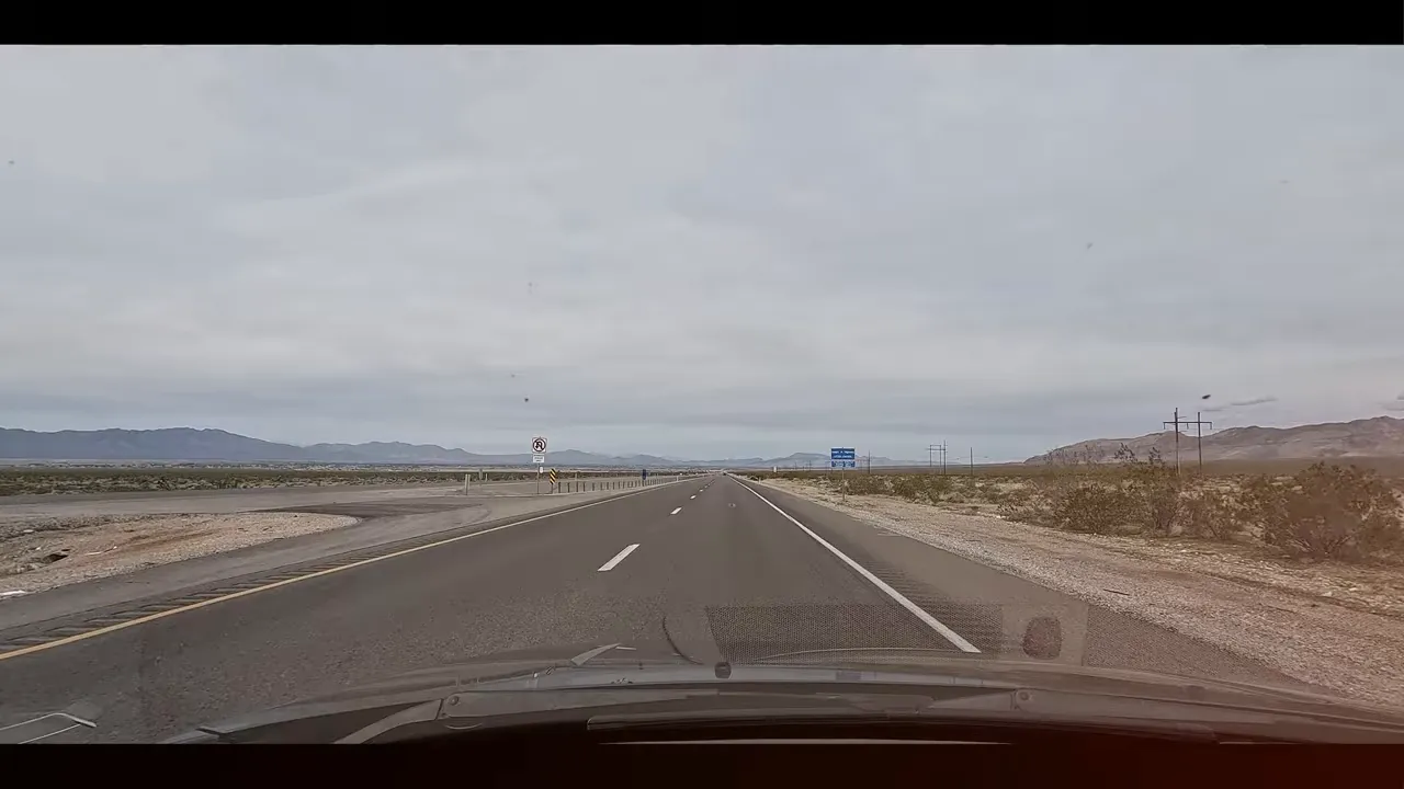View from inside a car driving on a two-lane road through the Nevada landscape near Pahrump