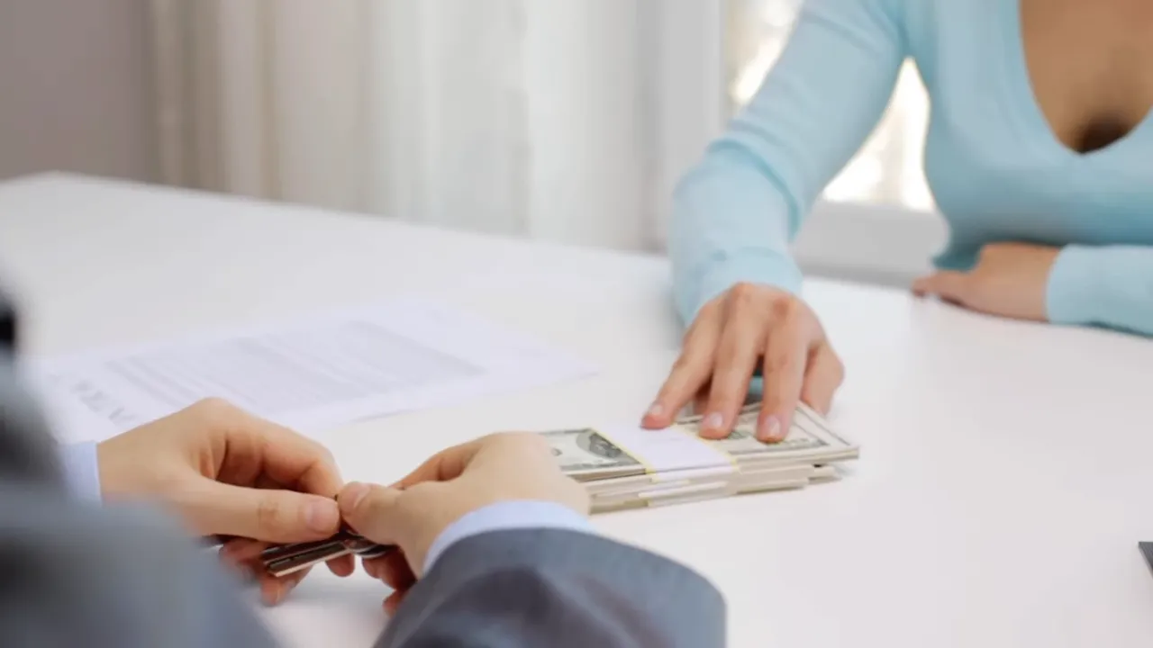 Hands signing paperwork at a home closing with escrow documents