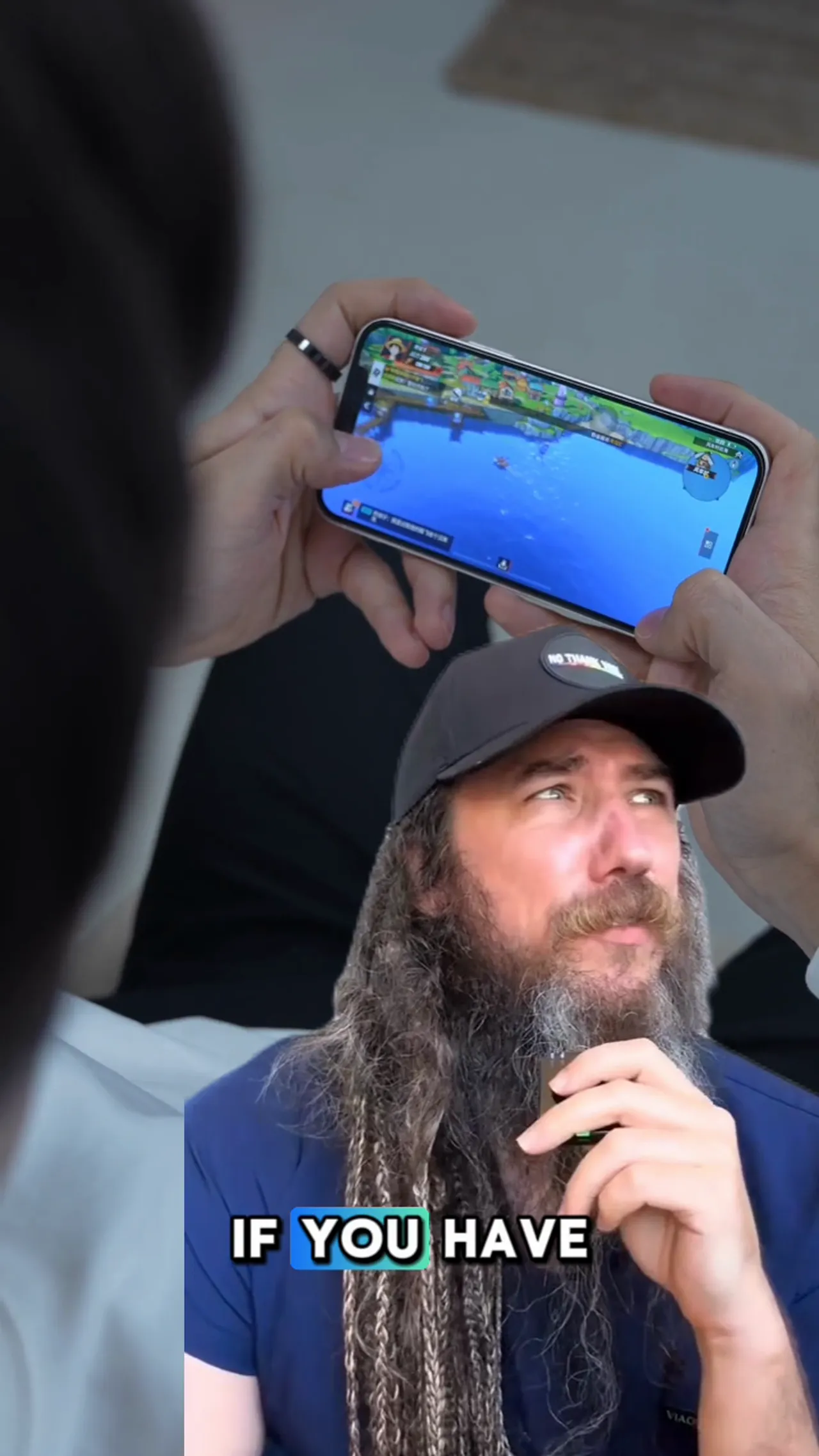 Hands holding a smartphone at chest level while the user looks down, showing forward head posture