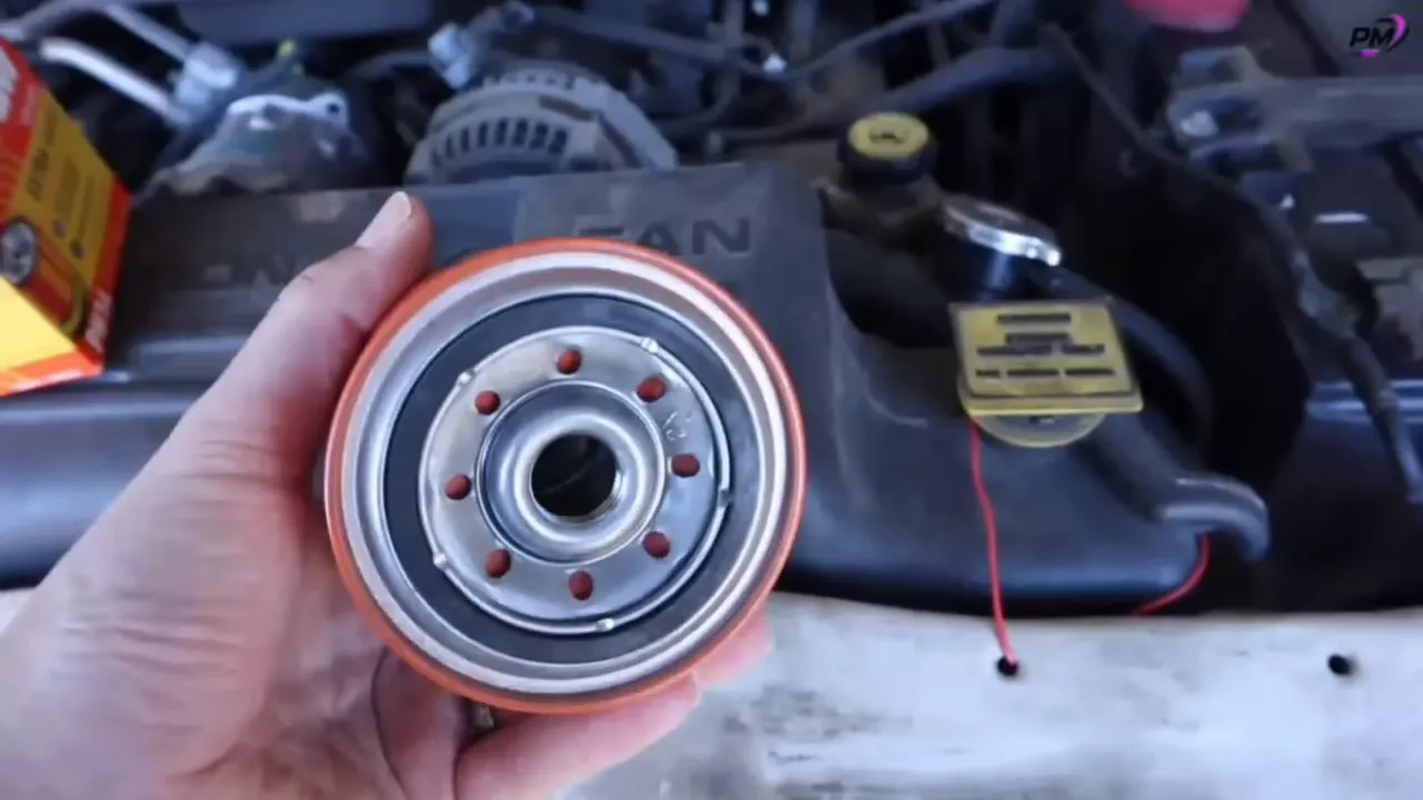Close-up bottom view of an orange FRAM oil filter showing the threaded center hole, inlet holes, and rubber gasket