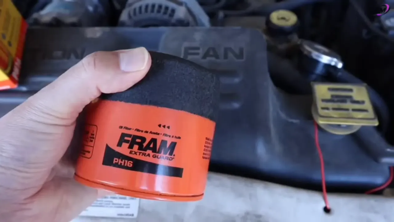Hand holding FRAM Extra Guard PH16 oil filter canister showing label