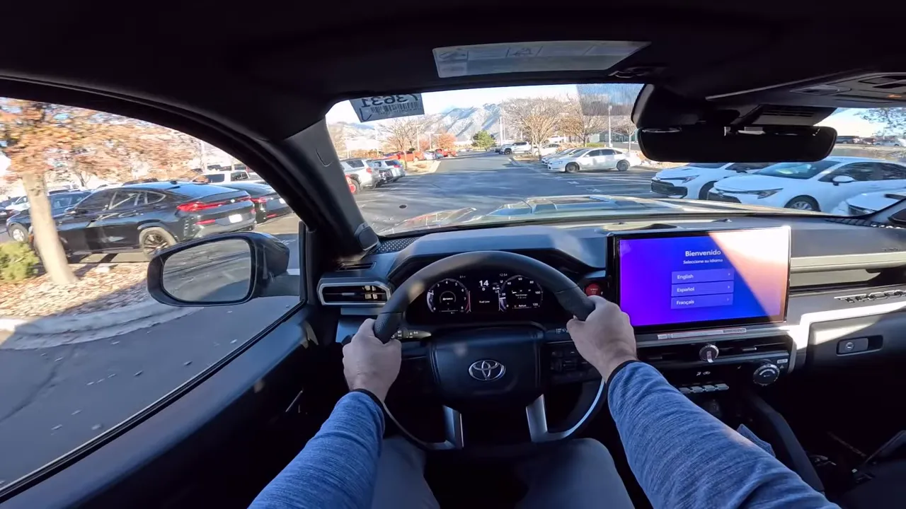 Centered POV of Toyota Tacoma showing steering wheel, clear digital gauge cluster and windshield view