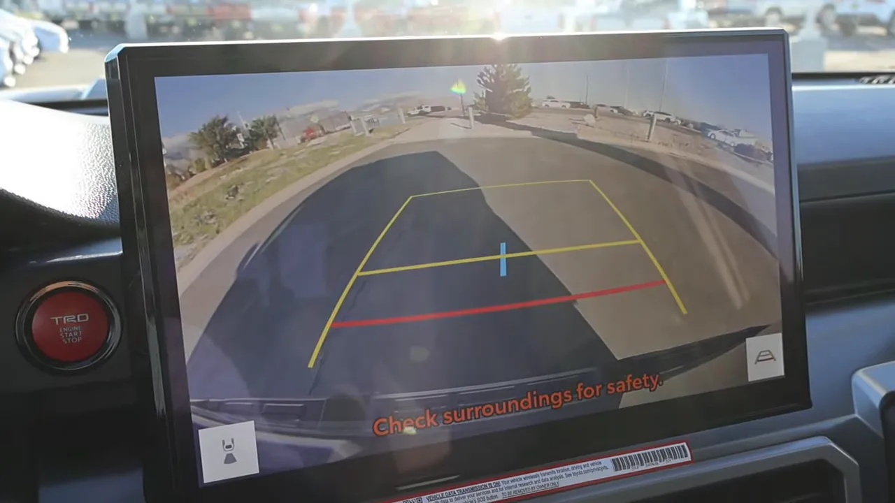 Center infotainment screen showing Tacoma rearview camera with yellow/red guidelines and surrounding view