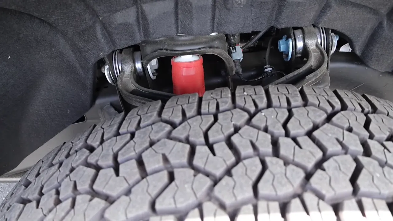 Close-up of front tire tread and red Rancho shock absorber on GMC Sierra 3500