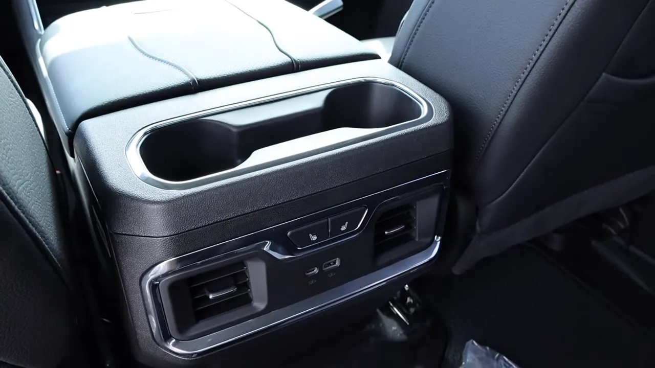 Rear center console of GMC Sierra Denali showing cupholders, air vents, USB ports and heated seat buttons