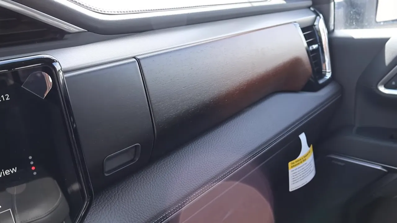 Close-up of GMC Sierra Denali interior showing wood dash trim, stitched leather dash pad and glovebox area