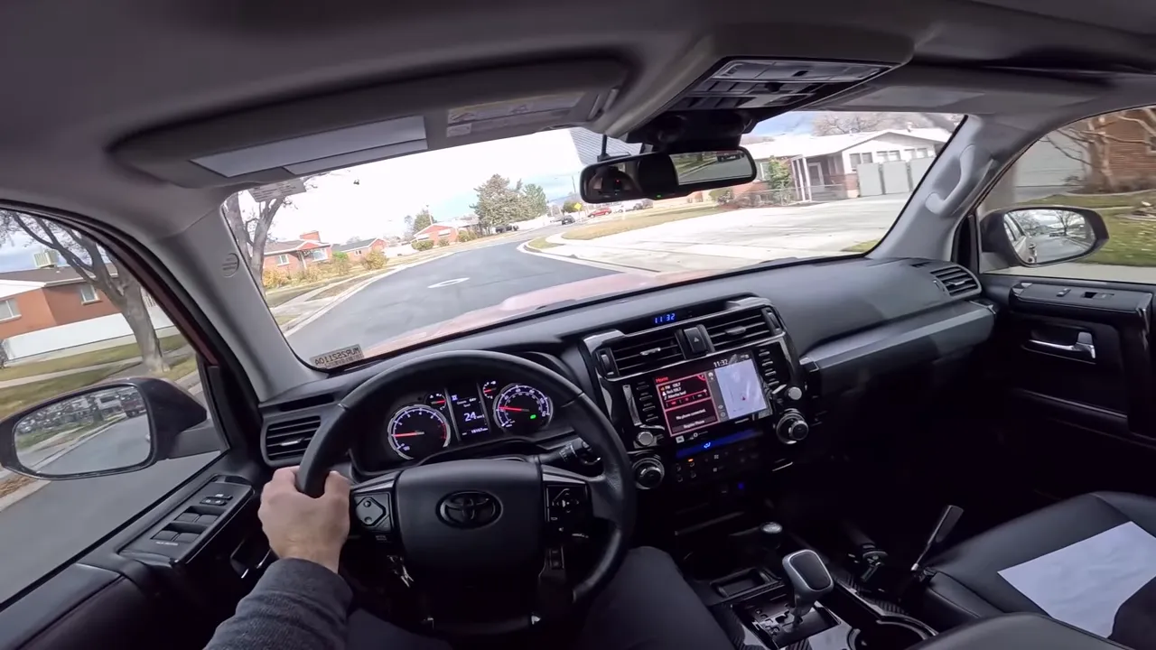 Wide driver's cockpit shot of a Toyota 4Runner showing steering wheel, speedometer and center infotainment screen while driving