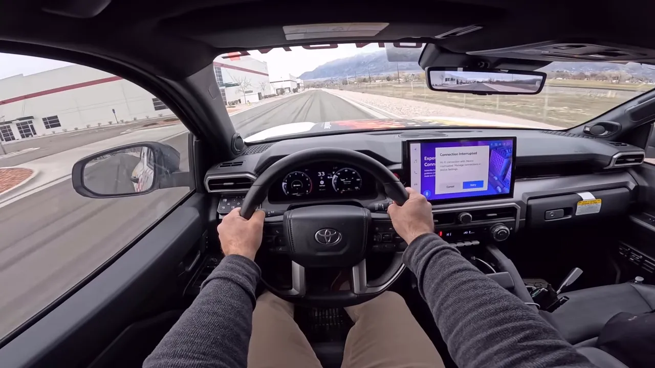 Driver POV inside Toyota 4Runner with hands on wheel, clear instrument cluster and center touchscreen