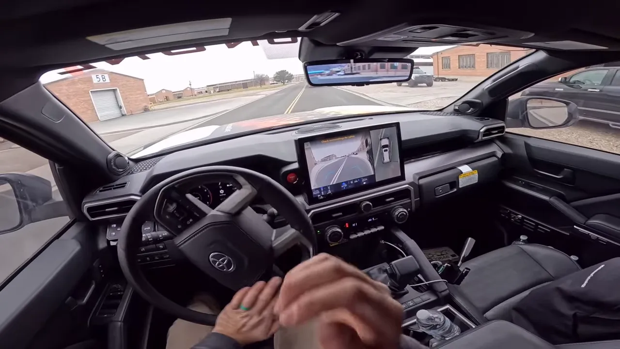 In-cabin driving view showing steering wheel, center touchscreen and road ahead illustrating ride and handling