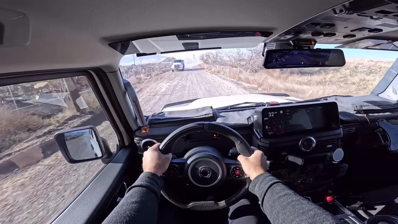 Driver POV in Grenadier on a dusty corrugated dirt road with a truck visible ahead