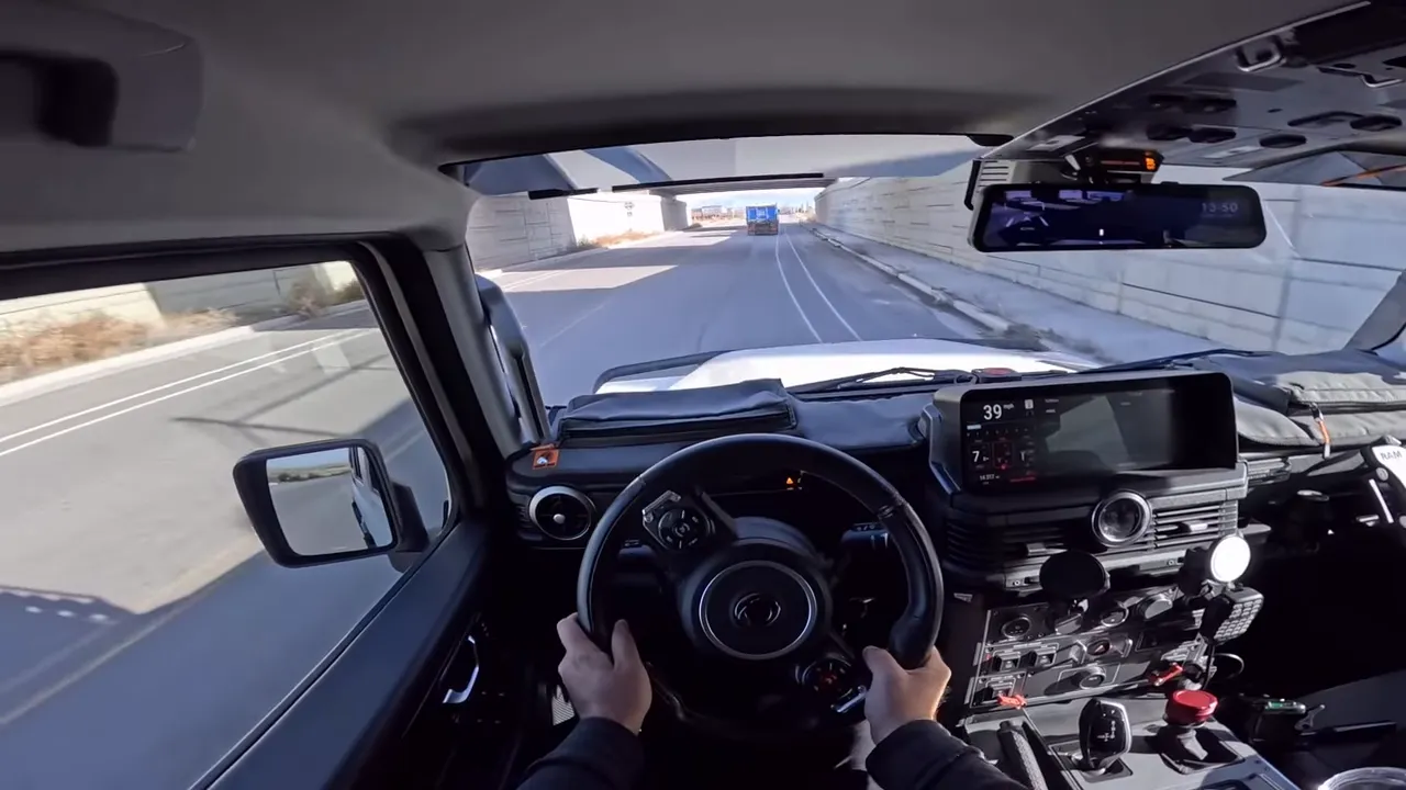 Front driver view inside Ineos Grenadier with hands on the wheel and a truck ahead, demonstrating composed handling