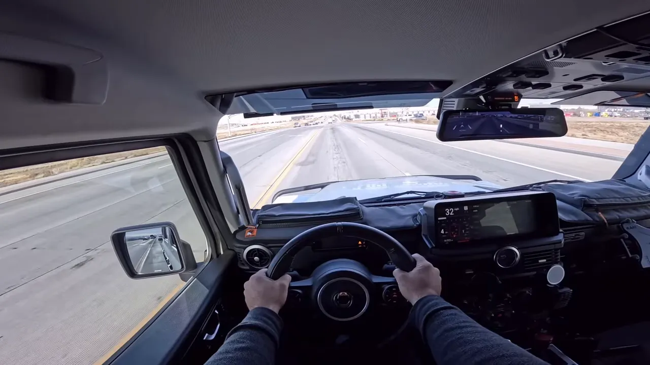 Ineos Grenadier interior driving view showing steering wheel, dashboard and road ahead