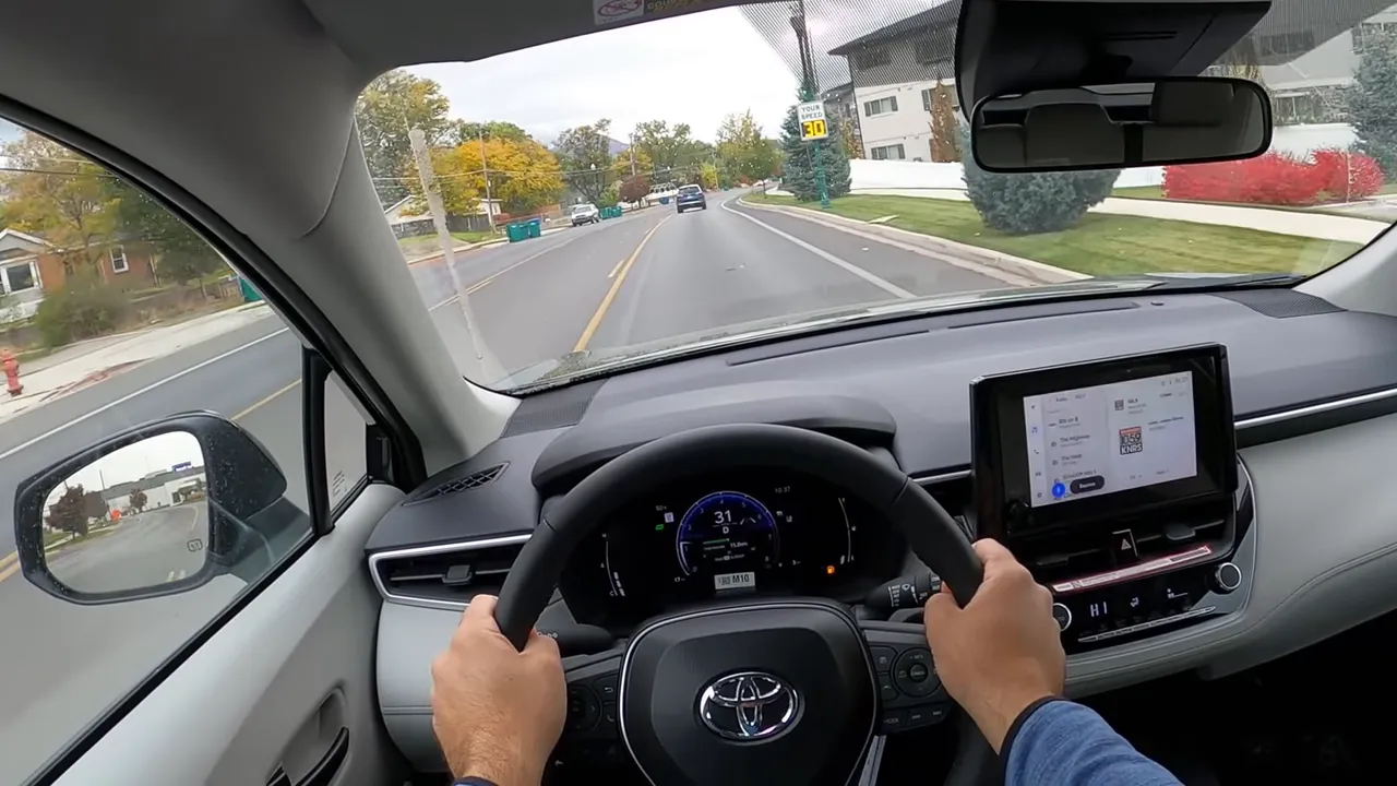 POV of Toyota Corolla Cross showing steering wheel, clear digital instrument cluster and road ahead with lane markings