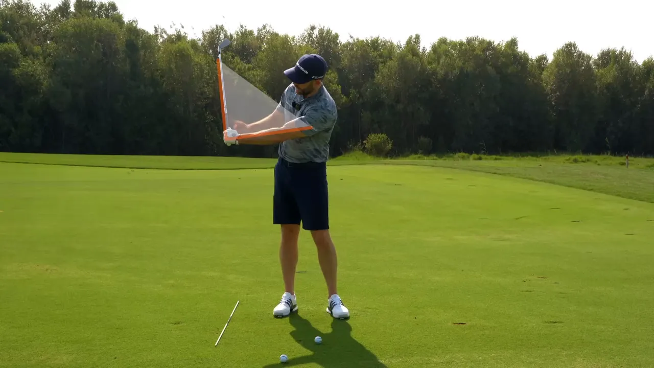 Instructor demonstrating the trail‑arm motion with an overlaid graphic showing elbow and wrist angles and the club path