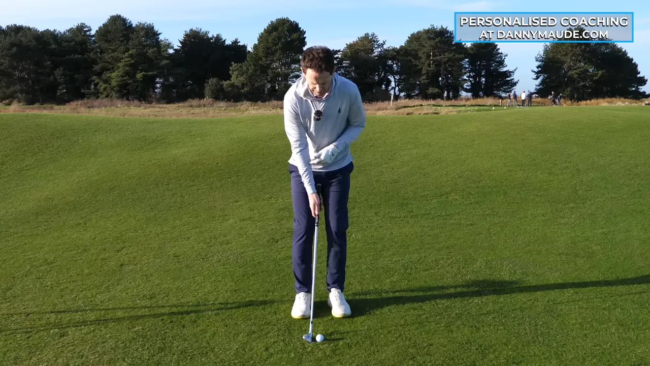 Frontal address shot of a golfer setting up with the club behind the ball and elbows close together