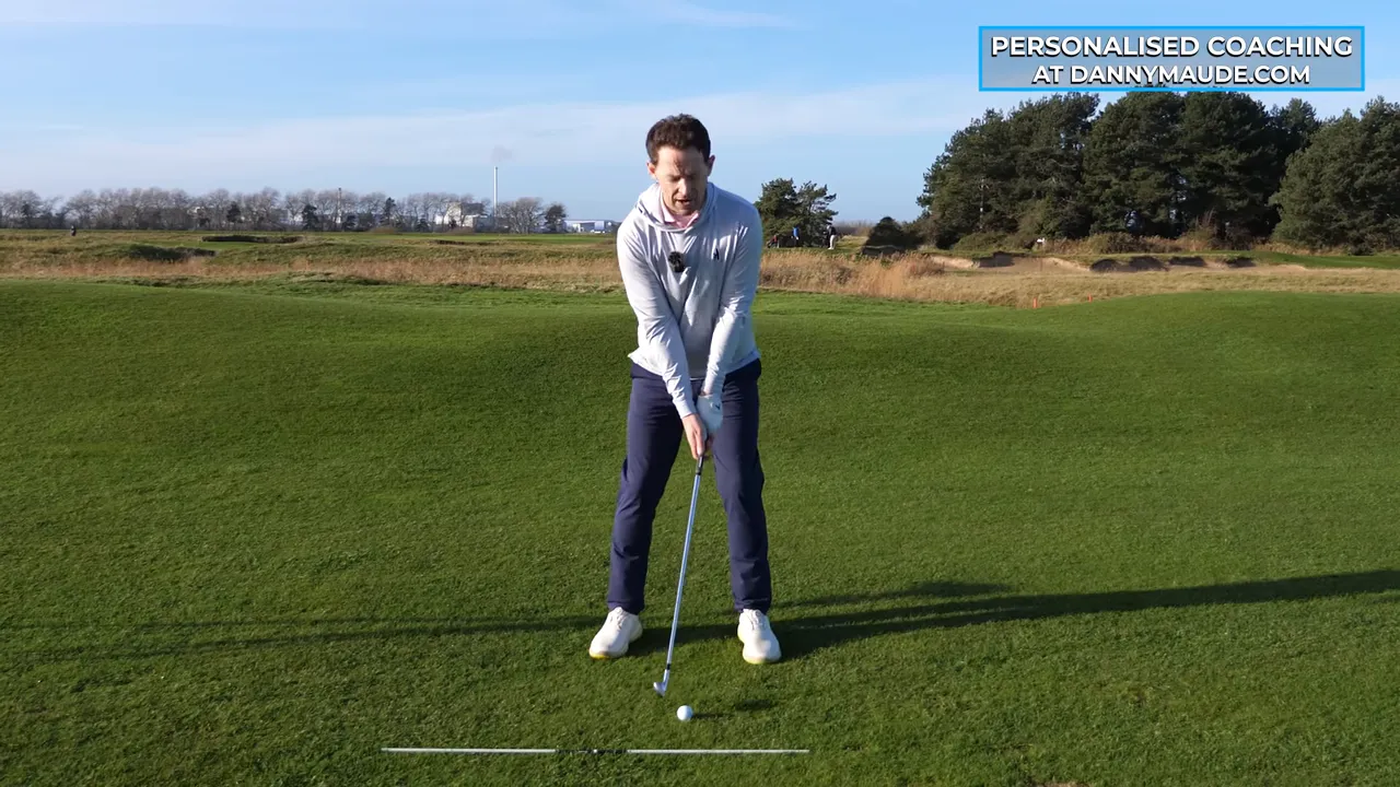 Frontal address shot of instructor setting trail elbow close to lead elbow with club behind the ball