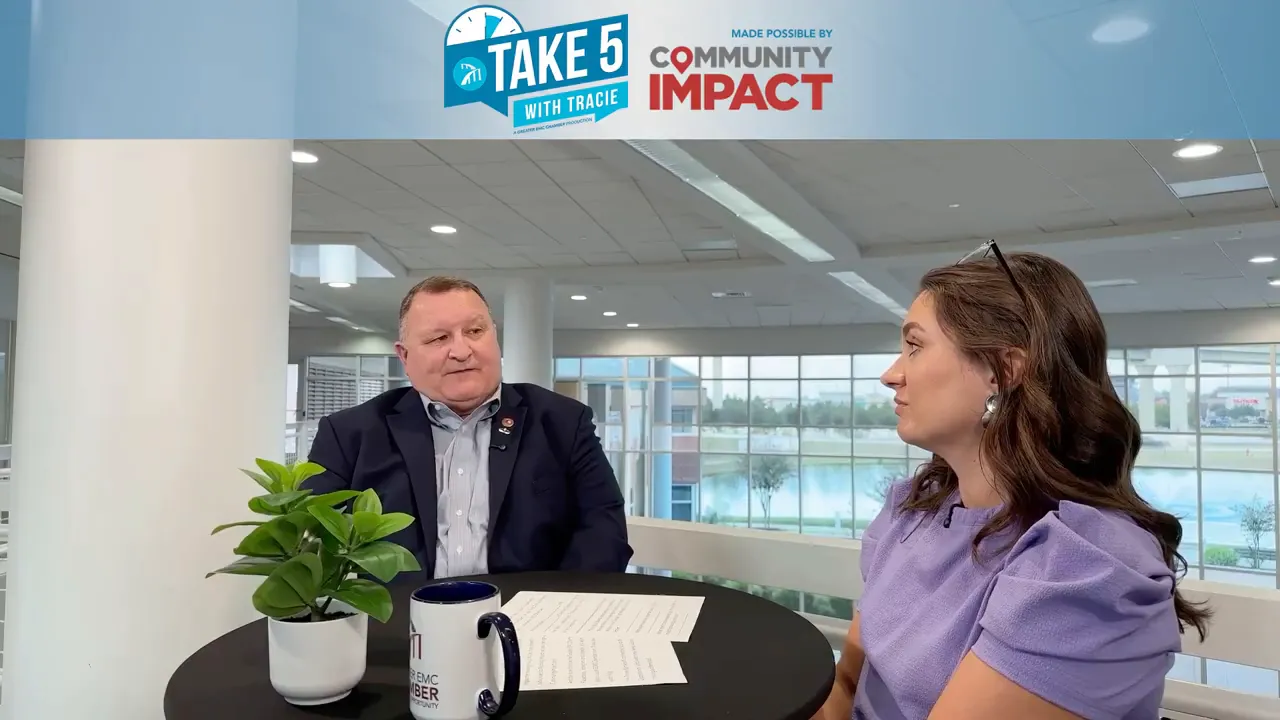 Two-person interview shot of Warren Porter speaking to Tracie Kamenoff in a bright atrium space.