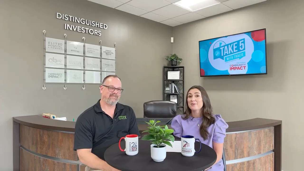 Tracie Kamenoff and Ross Davis seated at a table facing forward with the Take 5 screen visible in the background