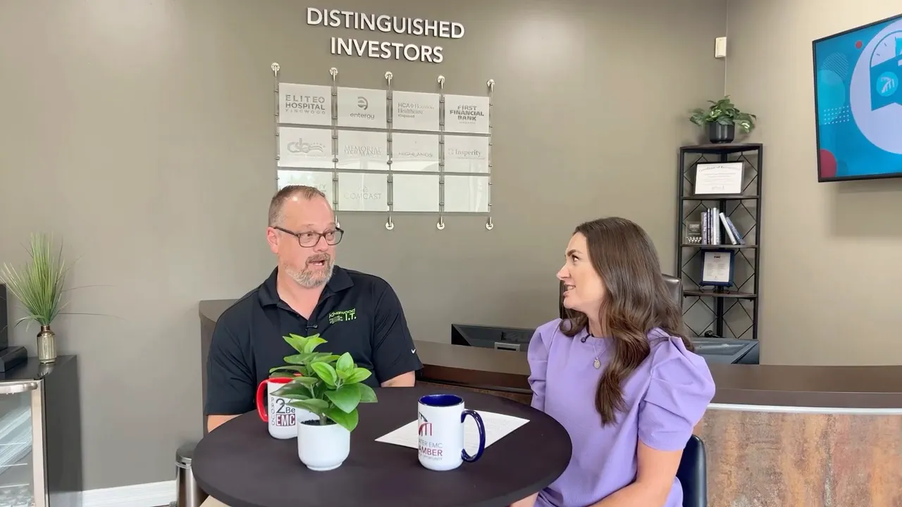 Ross Davis and Tracie Kamenoff talking across a small round table with investor plaques on the wall behind them