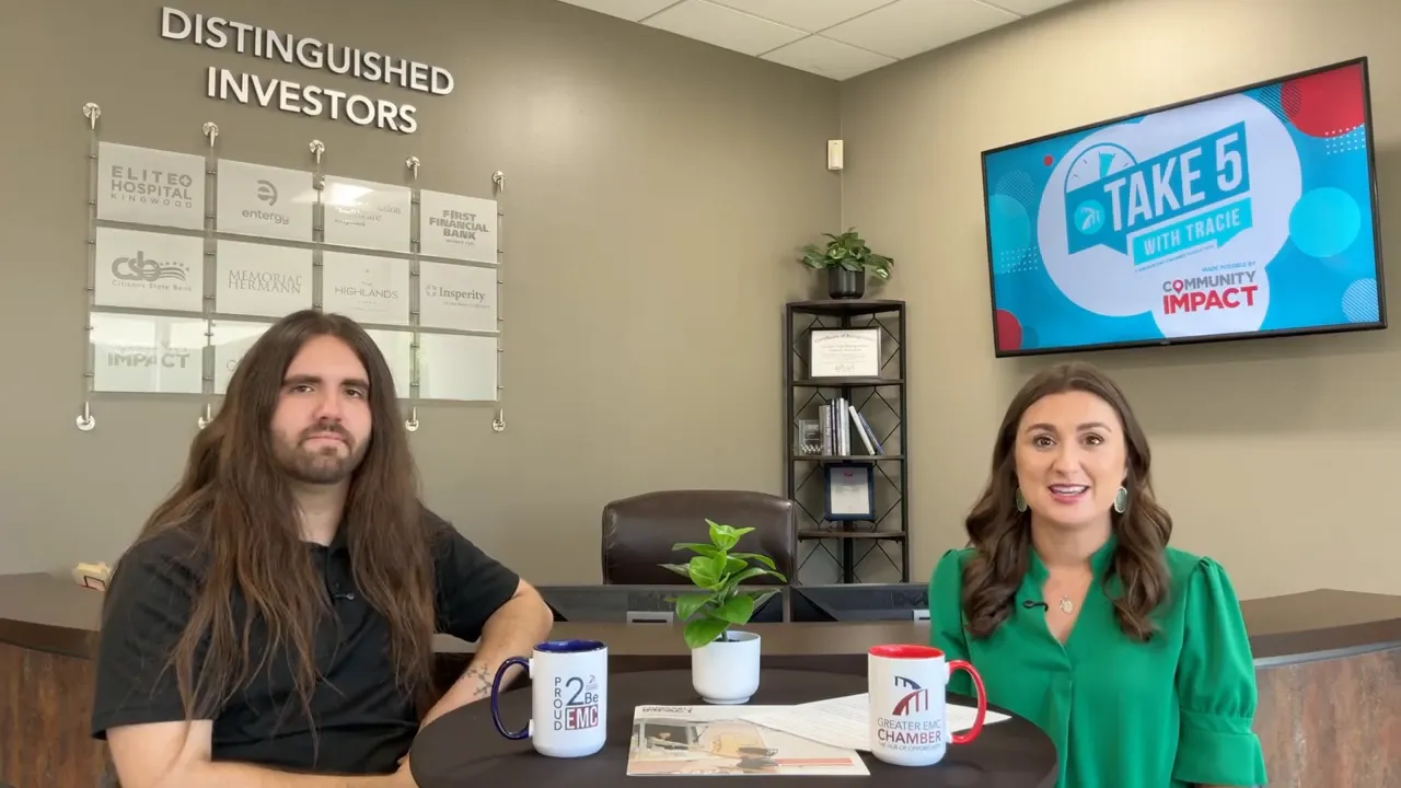 Tracie and Tyler seated at a table in the chamber office with a Take 5 screen and investor wall behind them