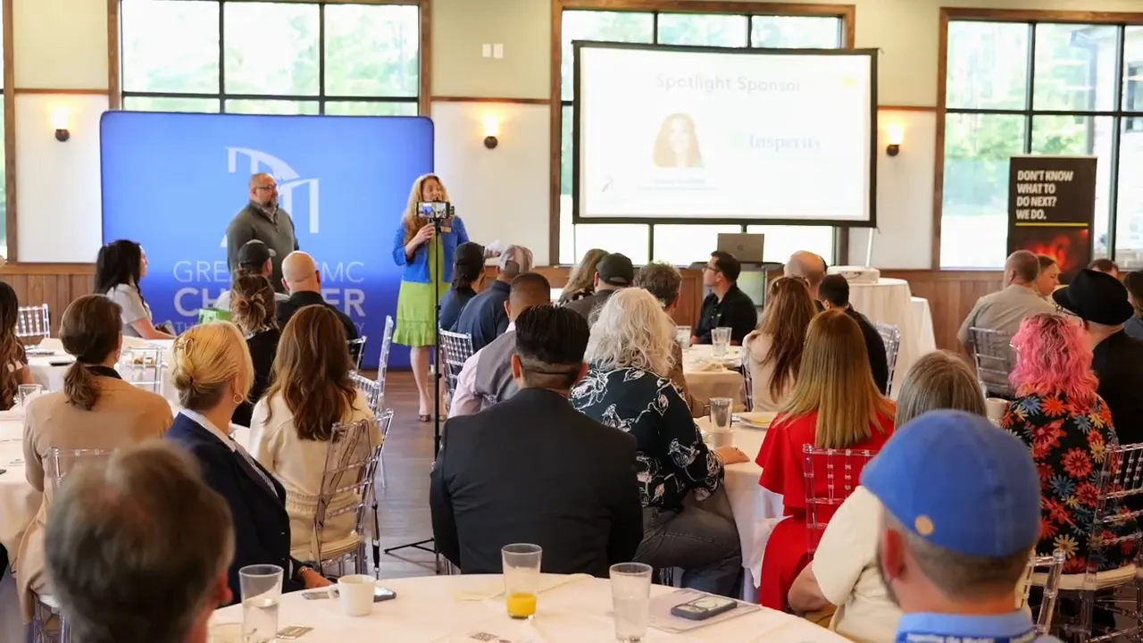 Insperity presenter addressing a seated audience at the Business Networking Breakfast with a spotlight sponsor slide on the wall screen
