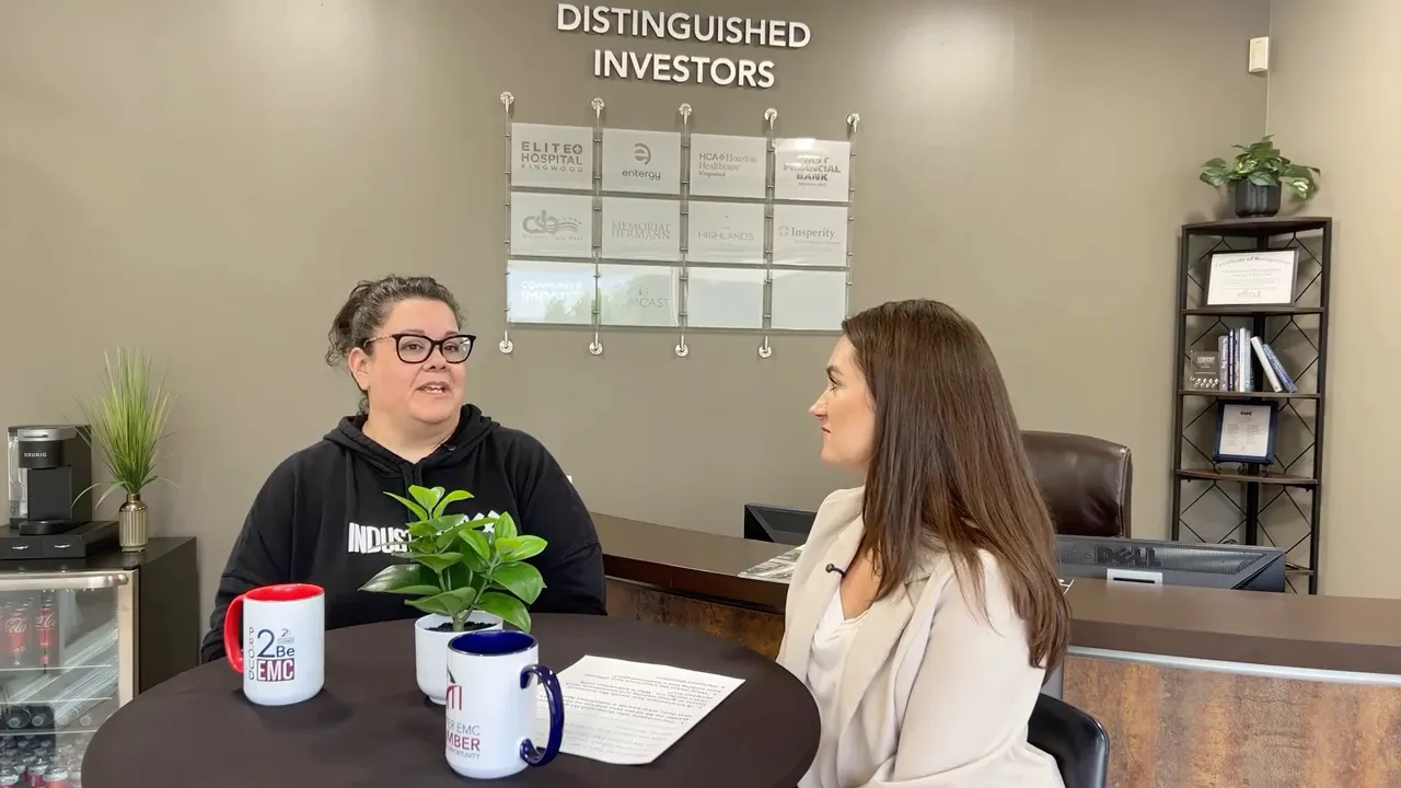 Kelly and Tracie talking across a small round table with mugs and a plant