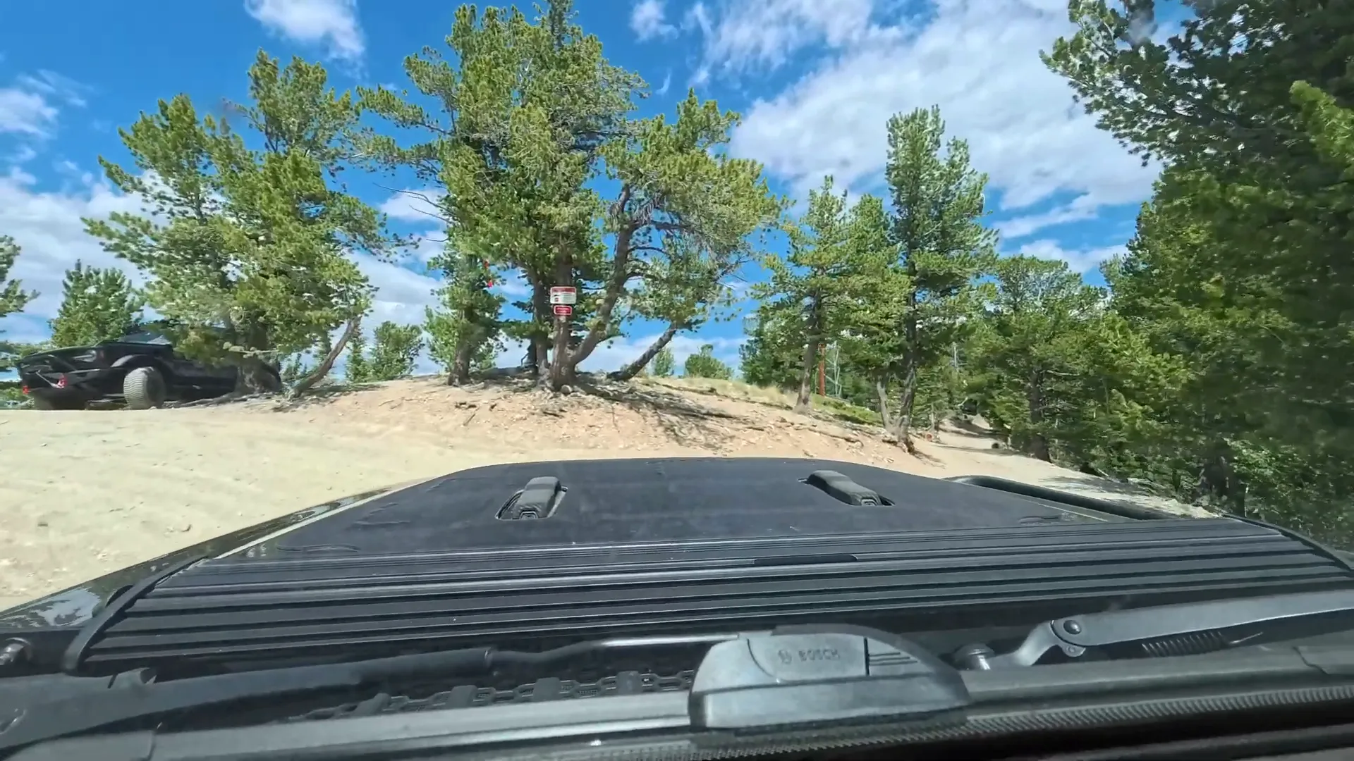 Small campsite area with vehicles nearby