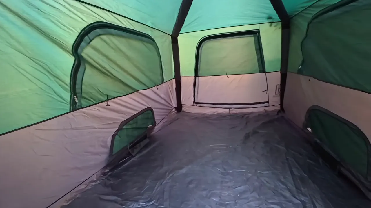 Empty tent interior with a broad floor, side windows, and arched supports