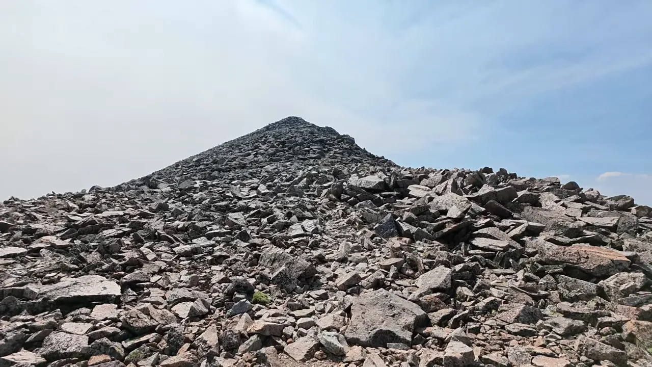 A rocky alpine ridge with a faint path through angular boulders toward a high point
