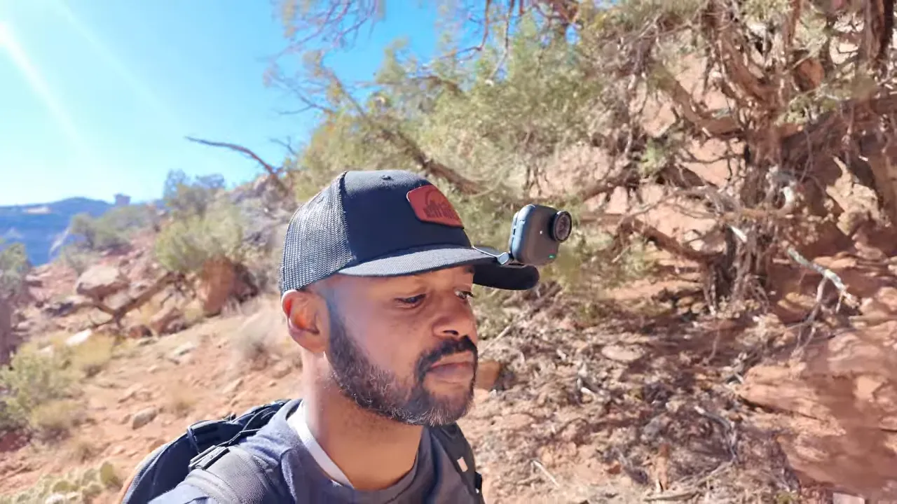 Person wearing a cap with an Insta360 Go Ultra camera mounted on the brim while hiking in a desert trail