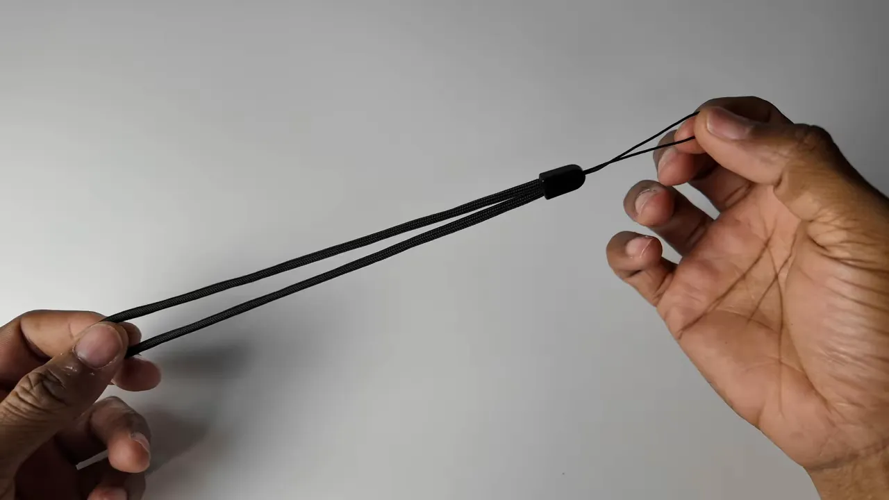 Hands holding the black nylon lanyard included with the Sofirn SK30 flashlight