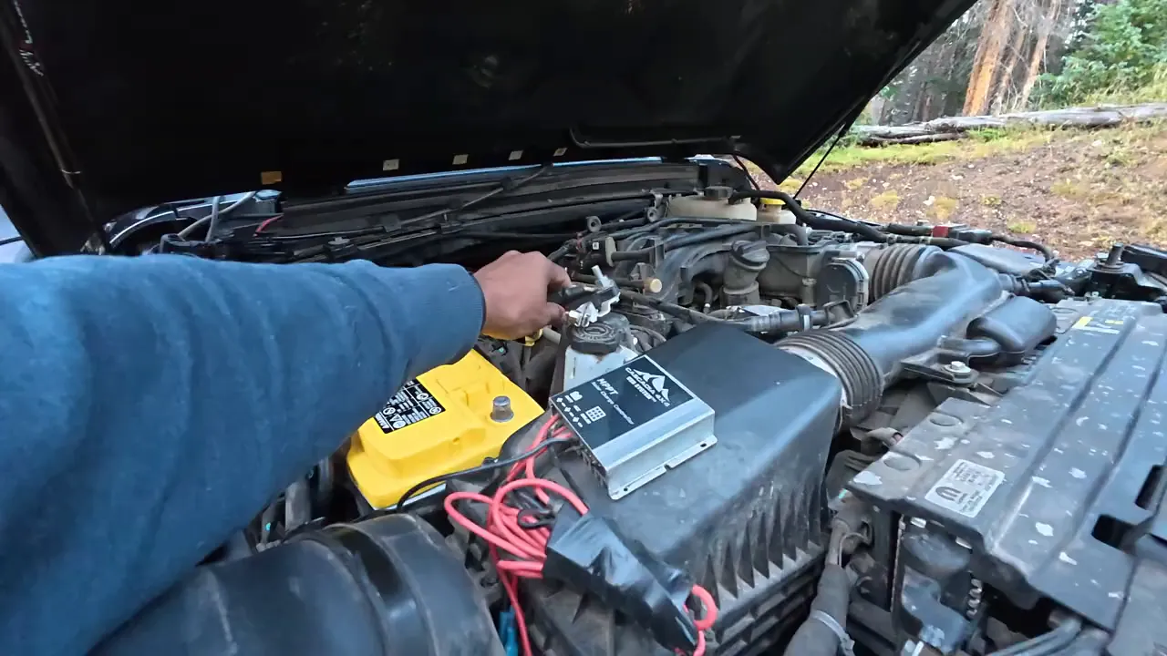 Reconnecting the Jeep battery on Billing Lake Trail with tools and battery terminals visible