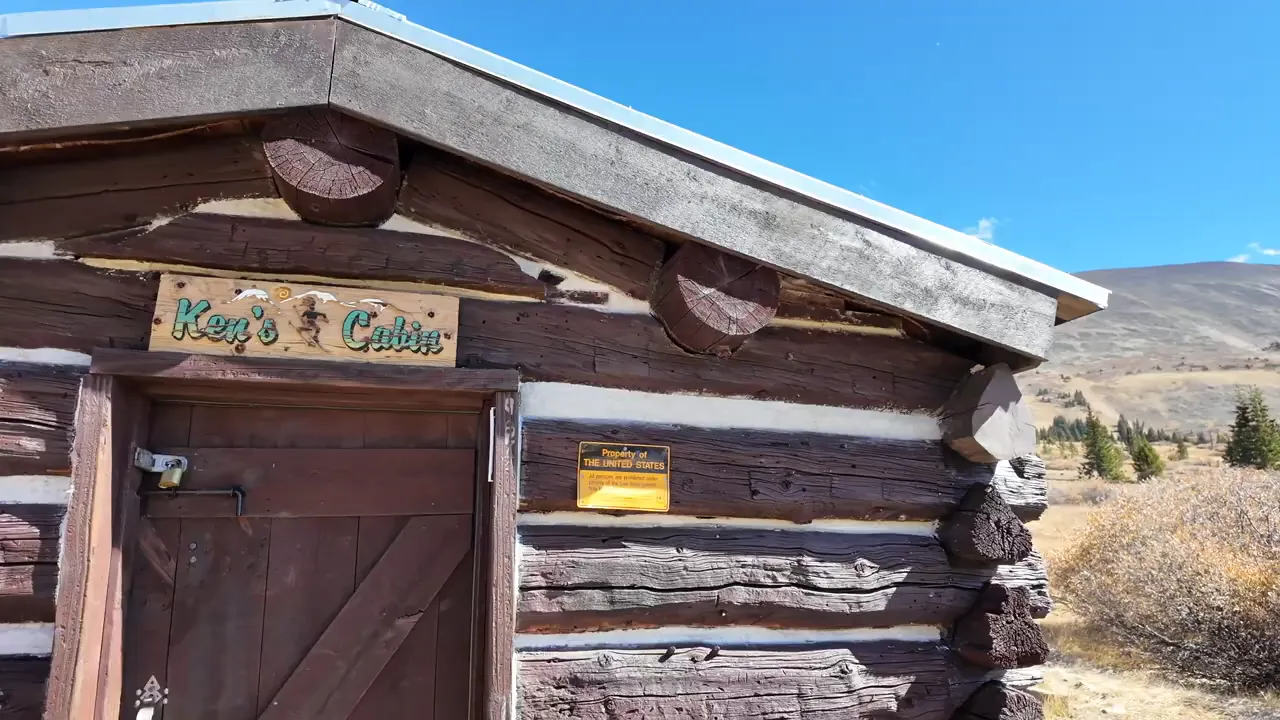 Interior of a small preserved cabin with a wood cook stove and benches