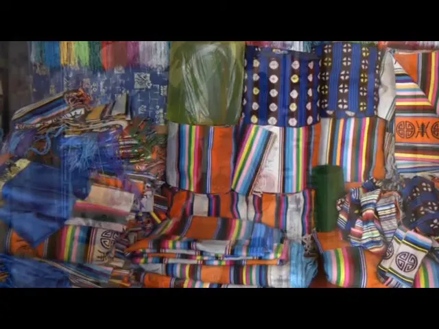 Tessuti tibetani colorati esposti in un mercato locale, con motivi tradizionali e righe multicolori