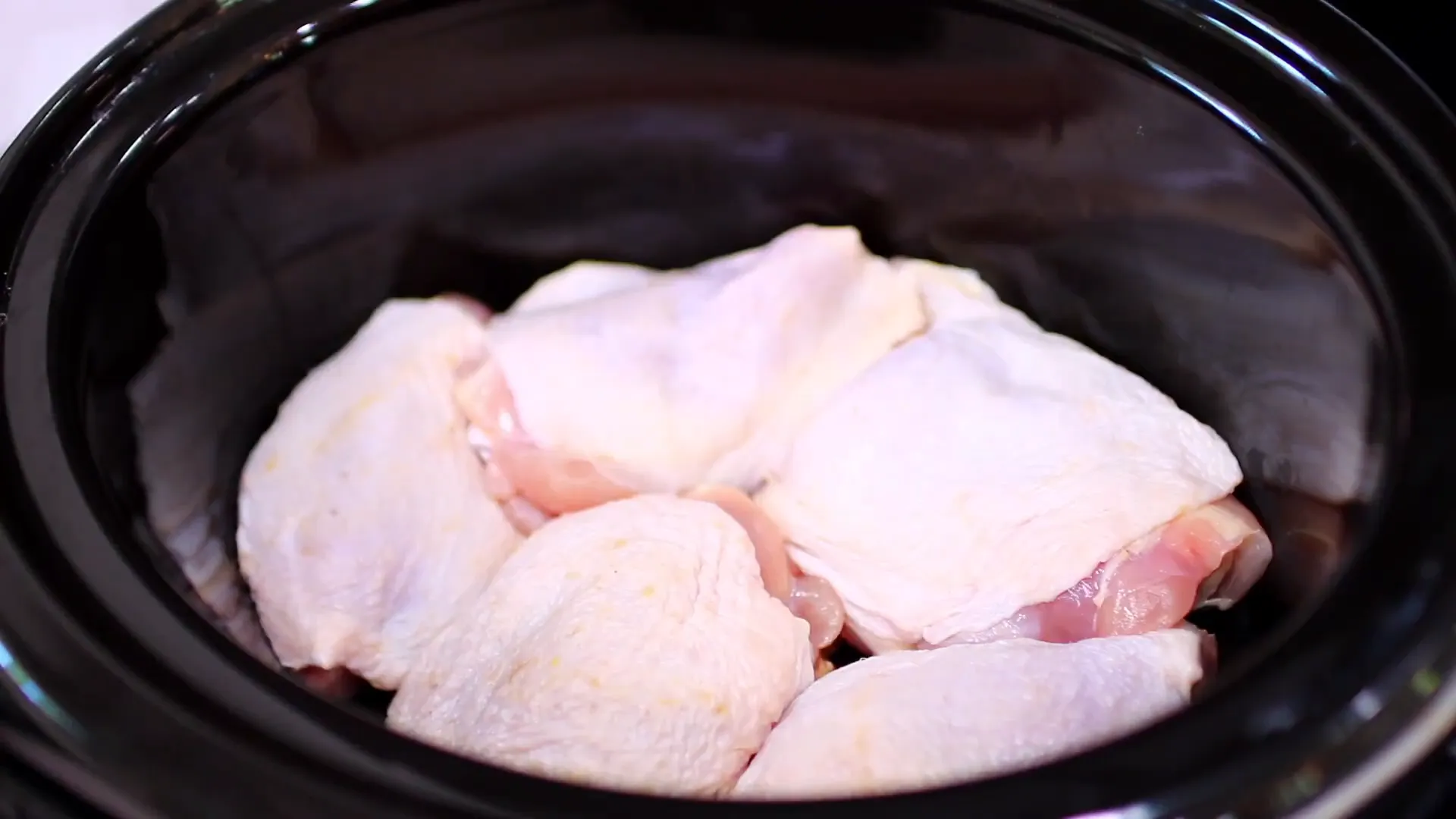 Chicken thighs arranged in slow cooker