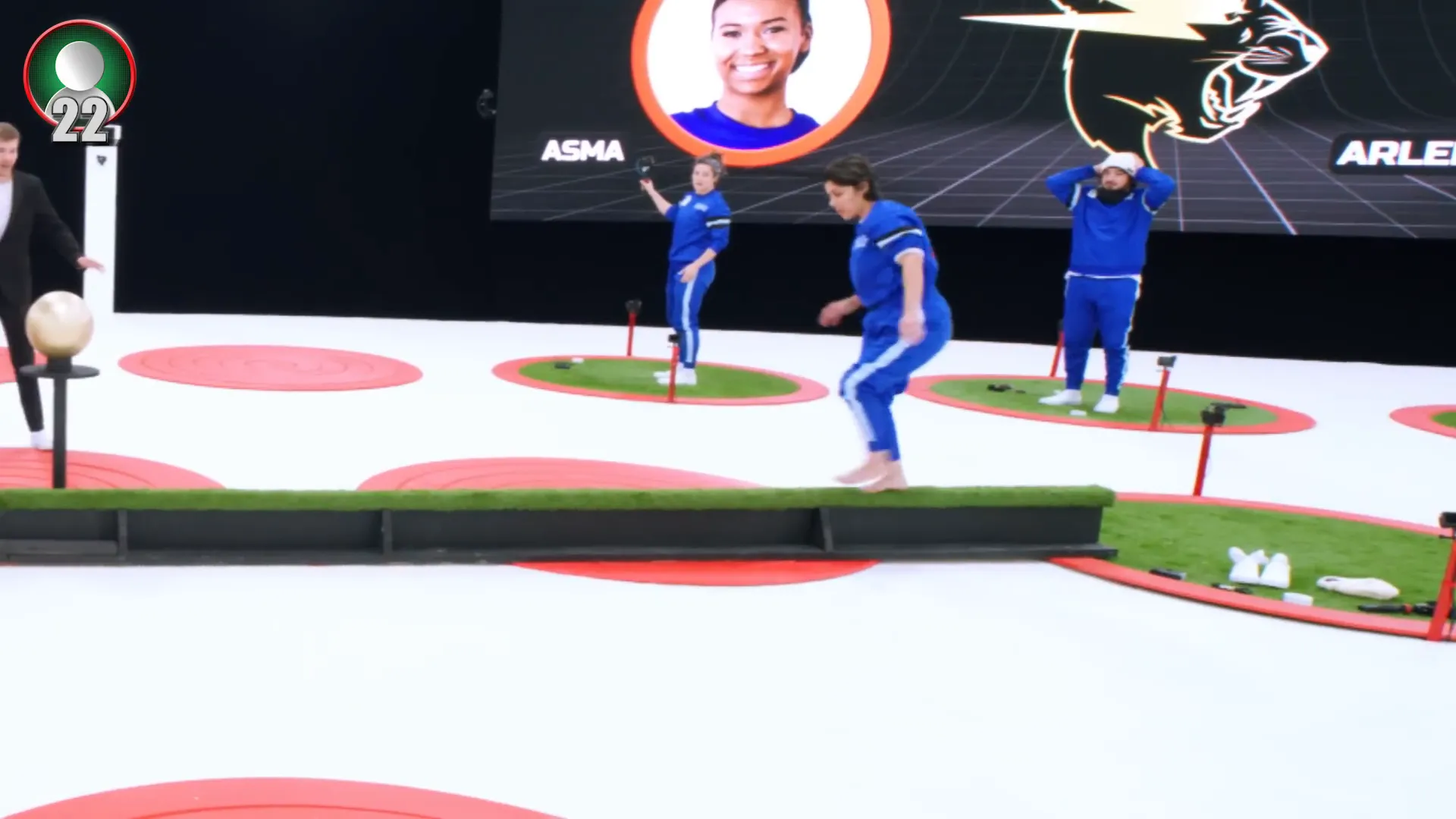 Contestants racing across a balance beam in head-to-head elimination rounds
