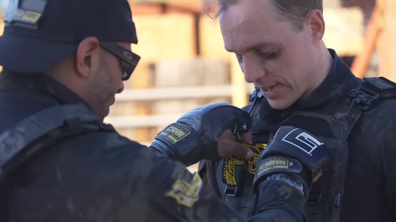 Close-up of gloved hands attaching an honorary patch to a trainee's plate carrier.