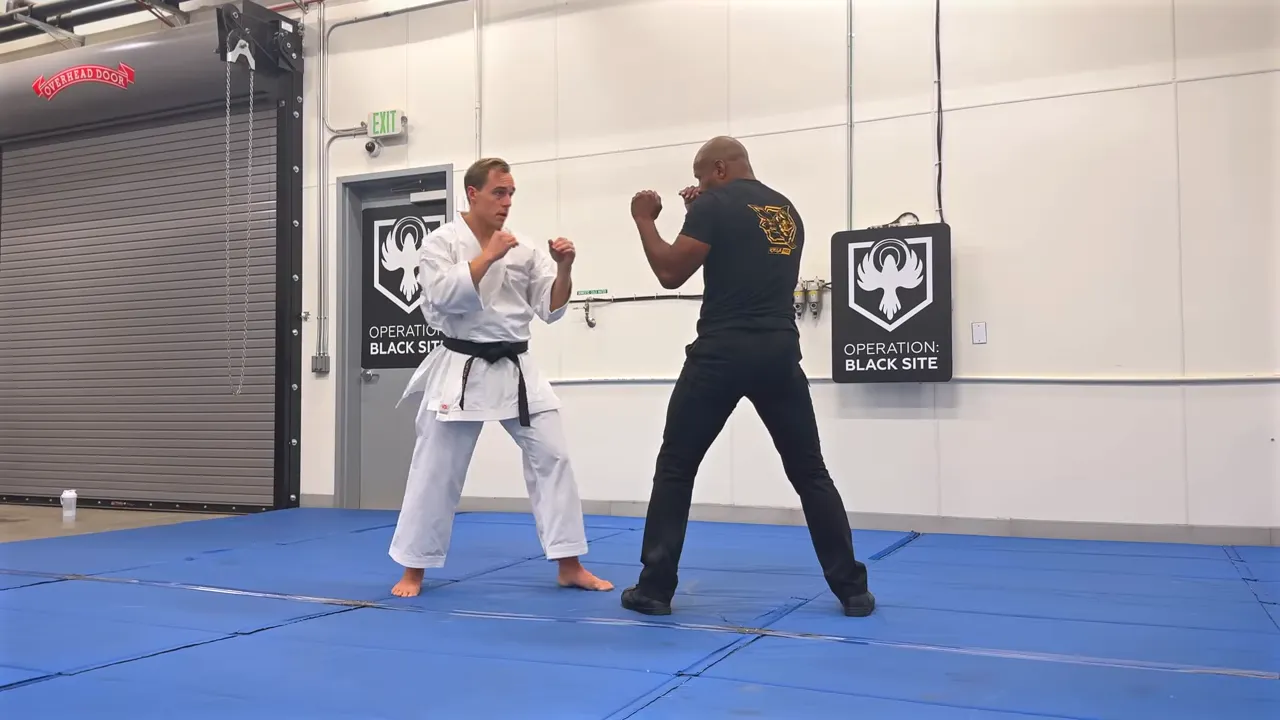 Two practitioners in a dojo stance facing each other to demonstrate distance, footwork, and bisecting lines