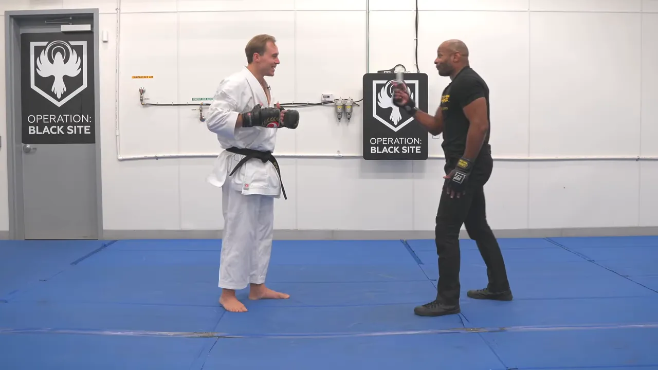 Two practitioners facing off on the mat in a training space with 'Operation: Black Site' signage