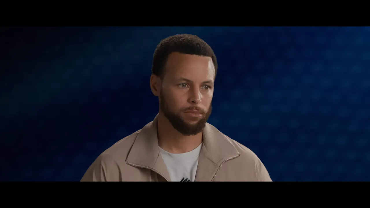 Close-up of a person speaking in the GOAT teaser trailer against a blue studio background