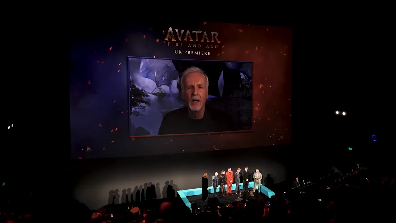 Wide theatre shot of the Avatar: Fire And Ash UK premiere &mdash; audience, cast on stage and a large branded screen showing a speaker.