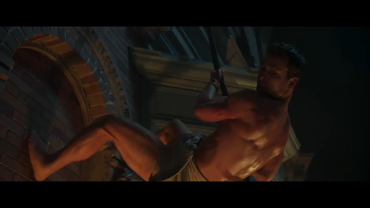 towel-clad man mid-climb on a building facade gripping a rope and pivoting, night exterior close-up