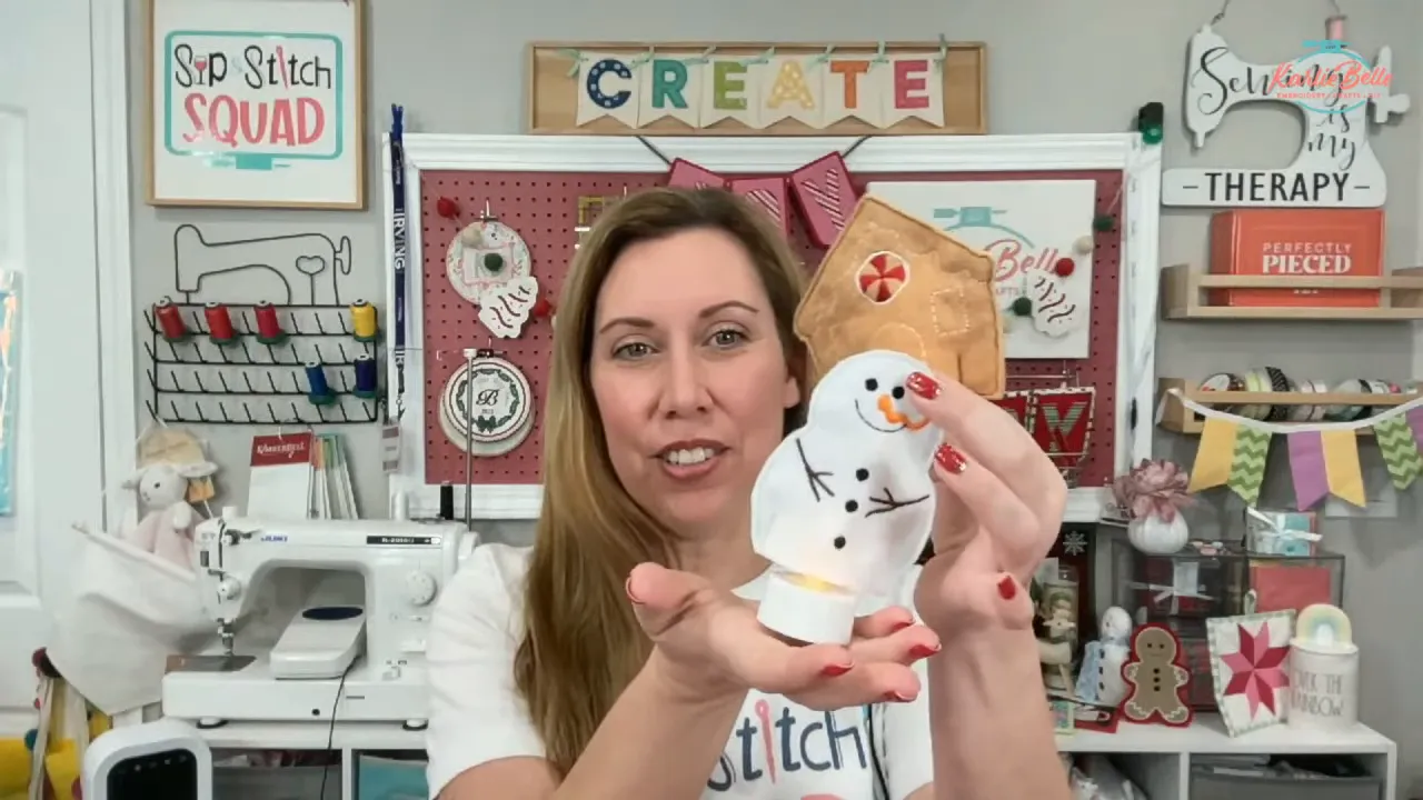 Close-up of creator holding a finished snowman in-the-hoop tea light cover glowing inside hands