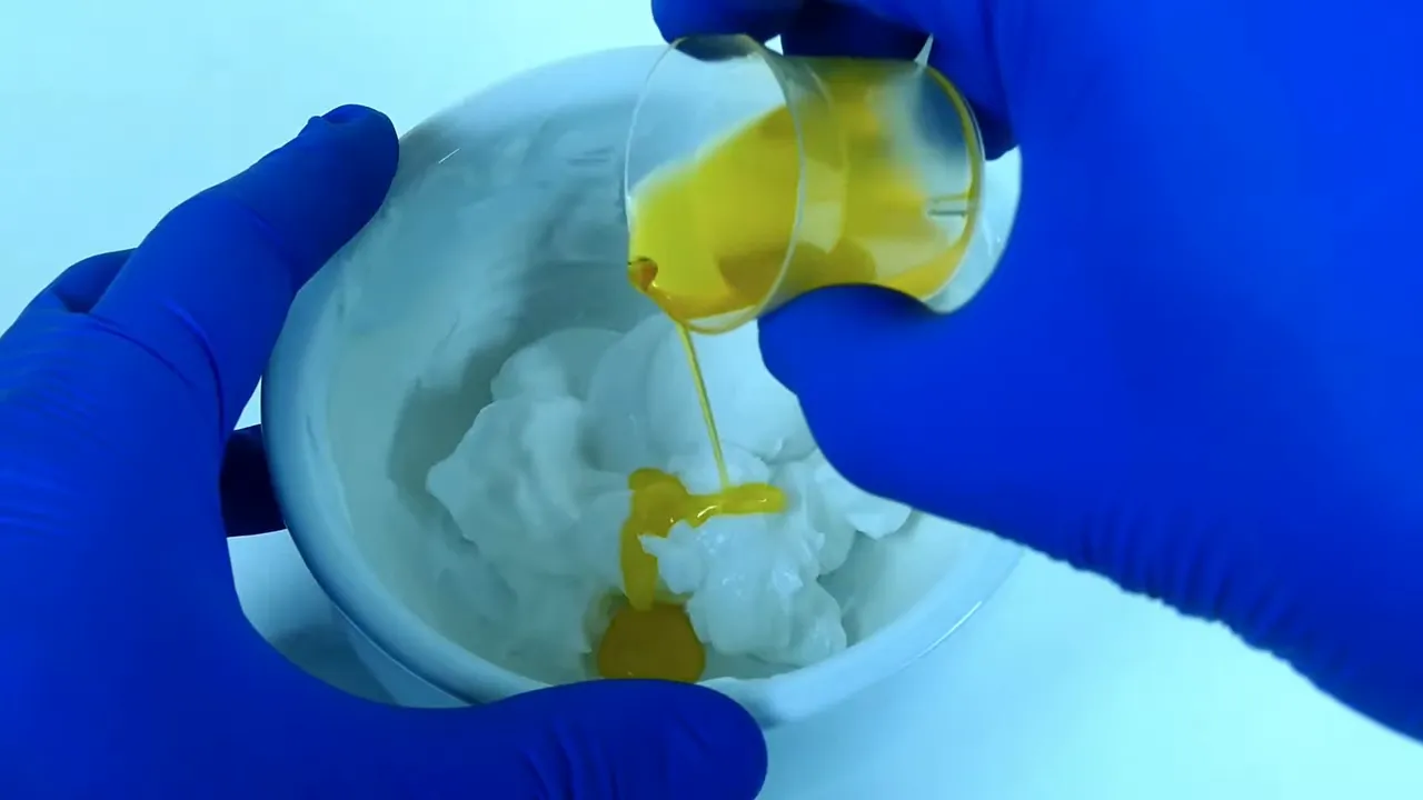 Aceite amarillo vertiéndose sobre la emulsión blanca dentro del mortero