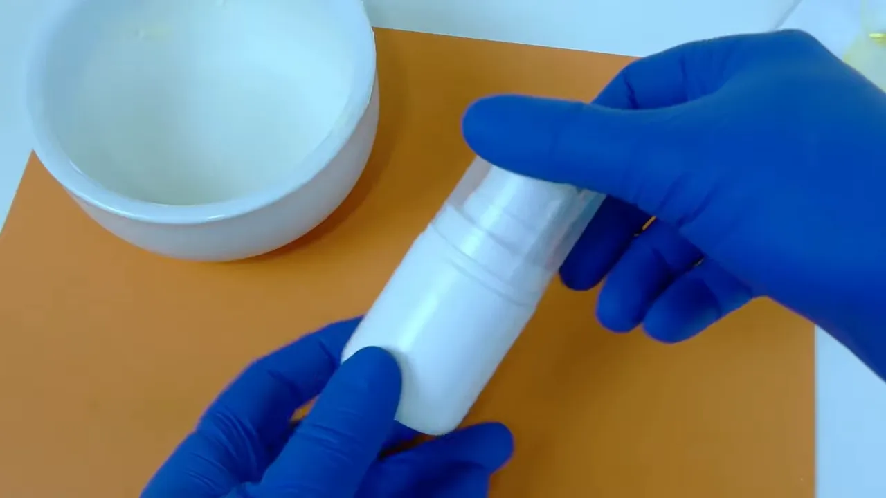 Envase airless blanco opaco sostenido con guantes azules