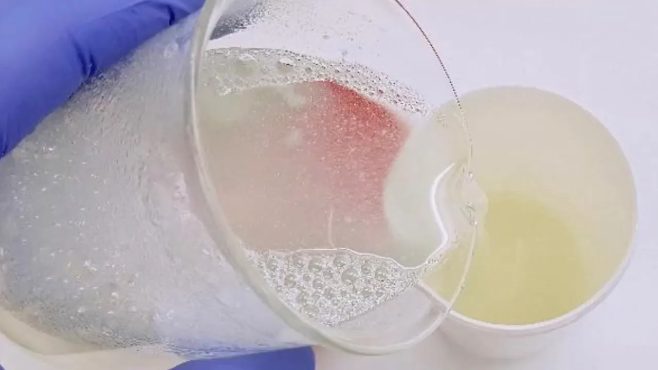 Vertido del solubilizado de alfa-bisabolol en medio acuoso con guante azul y espuma
