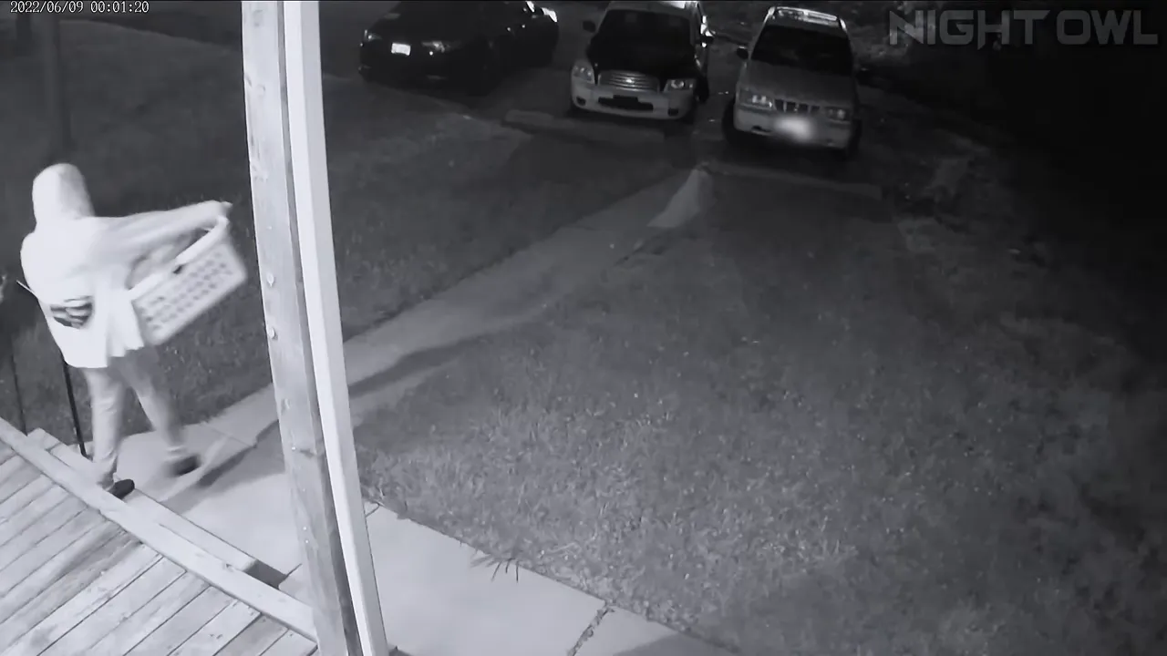 CCTV still of a man carrying a white laundry basket down a quiet street